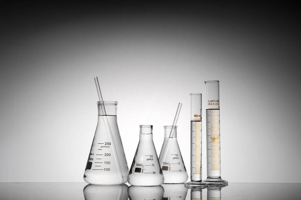 A closeup shot of transparent laboratory flasks, beakers, and tubes - Fotoğraf, Görsel
