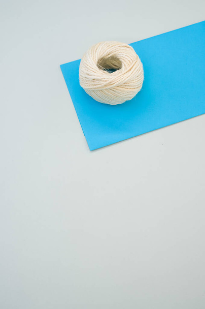 A vertical shot of white cord rope on a piece of paper on a gray background - Foto, Imagem