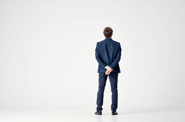 rear view of a man in a suit on a light background gesturing with his hands in full growth - Фото, изображение