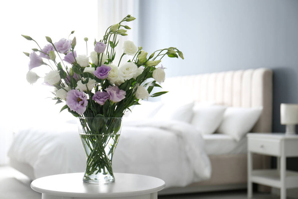 Beautiful bouquet with Eustoma flowers on table in bedroom. Space for text - Photo, Image