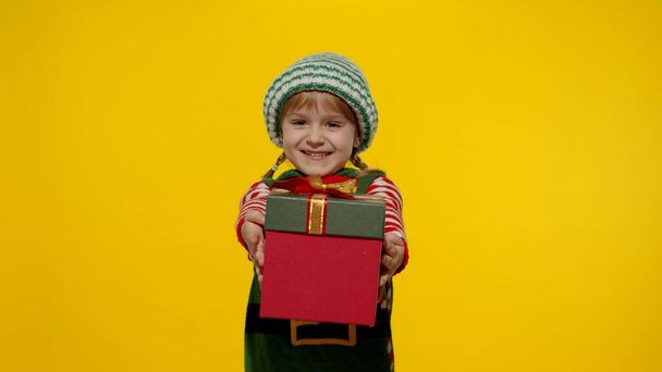 Kid girl Christmas elf Santa helper giving present gift box to camera. Happy New Year holidays - Photo, Image