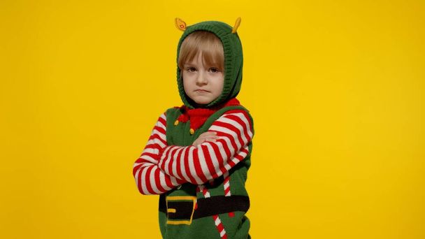 Schockiertes Mädchen im Weihnachtselfen-Helferkostüm. Kind schaut in Kamera und fragt, was - Foto, Bild