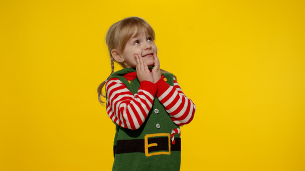 Kid girl Christmas elf Santa helper steepls fingers waiting for gift box. Child in New Year holidays - Foto, Imagem