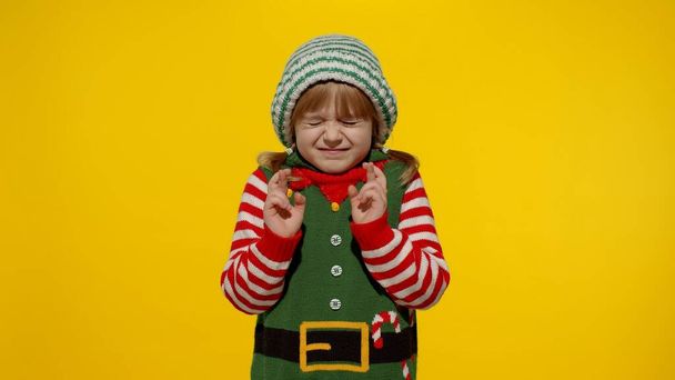 Concepto de deseo navideño. Niño adolescente chica en Navidad elfo Santa ayudante traje haciendo un deseo, reza - Foto, Imagen