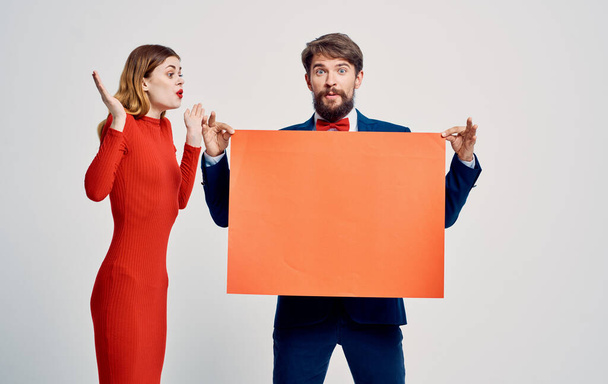 homem emocional em um terno e laço com um mockup em suas mãos e uma jovem mulher - Foto, Imagem