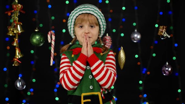 Joulutoivomus. Kid teini tyttö jouluna tonttu Santa auttaja puku tekee toiveen, rukoilee - Valokuva, kuva