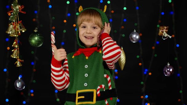 Menina criança no elfo de Natal Santa Claus traje auxiliar fazendo chamadas de parabéns no telefone móvel - Foto, Imagem