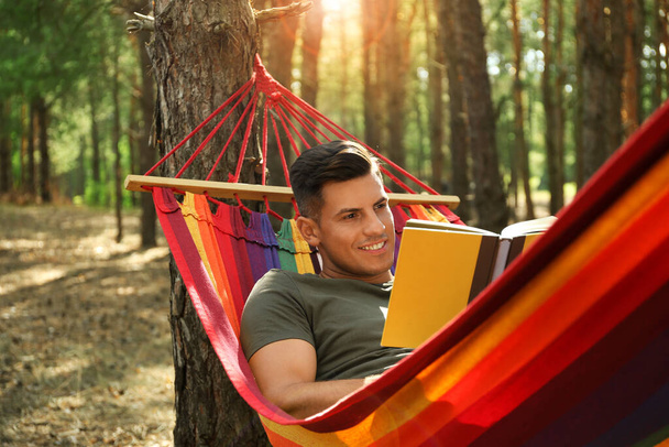 Man with book relaxing in hammock outdoors on summer day - Foto, Bild