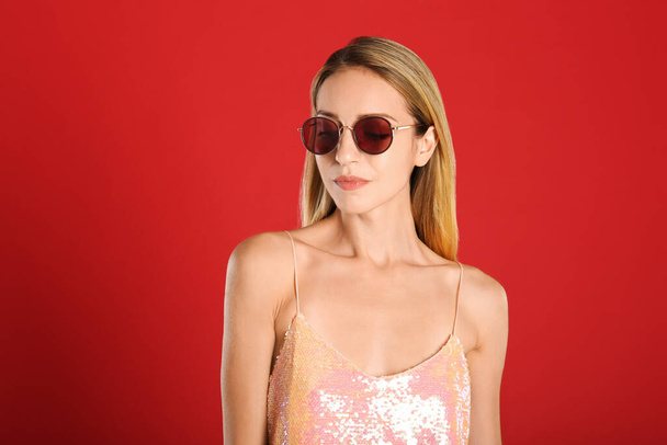 Beautiful woman in stylish sunglasses on red background - Photo, Image