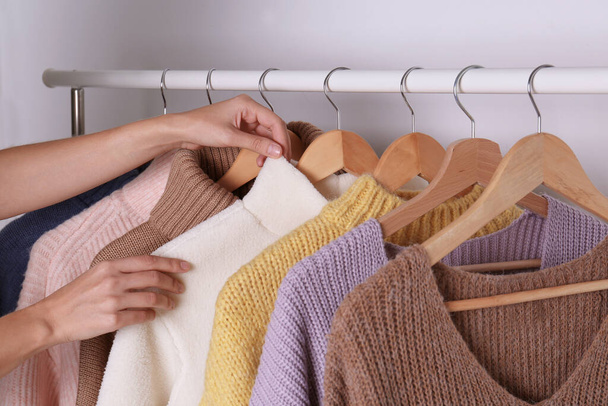 Woman choosing sweater on rack against white background, closeup - Fotó, kép