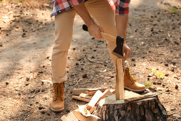 Man chopping firewood with axe in forest, closeup - Fotó, kép