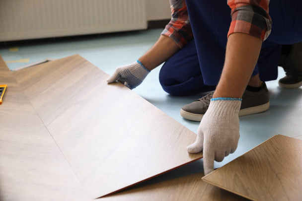 Worker installing laminated wooden floor indoors, closeup - Foto, Imagen