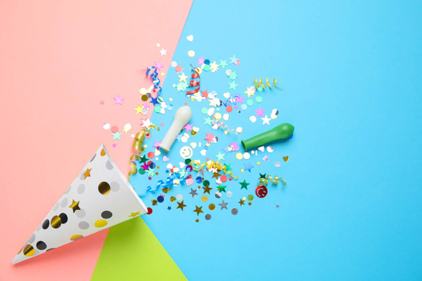 Bright confetti with party cracker on color background, flat lay - Foto, Bild