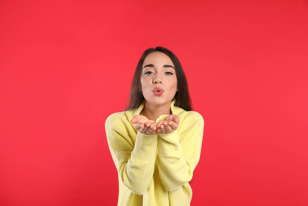 Beautiful young woman wearing yellow warm sweater on red background - Foto, Imagen