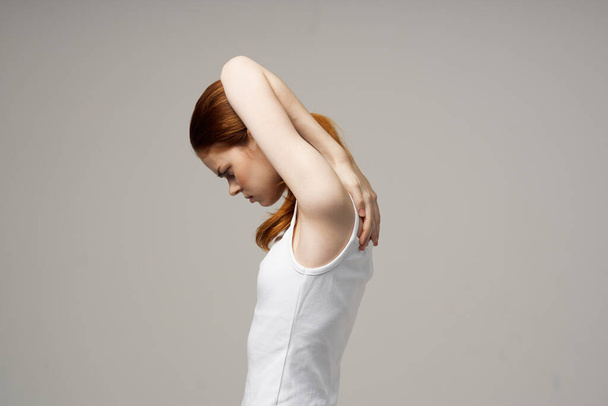 red-haired woman in white t-shirt touching herself with hands on gray background cropped view - Photo, Image