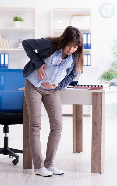Pregnant woman struggling to do work in office - Foto, imagen
