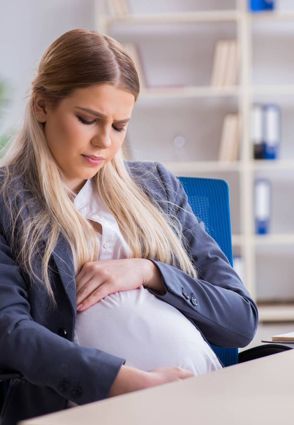Pregnant woman employee in the office - Foto, imagen