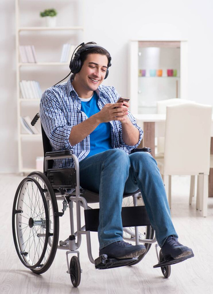 Tekerlekli sandalyede müzik dinleyen engelli adam. - Fotoğraf, Görsel