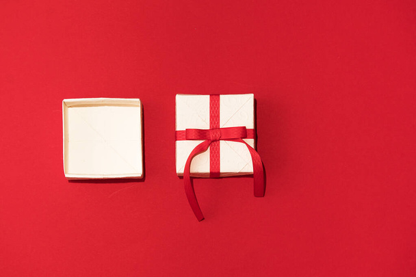Caja de regalo blanca con cinta roja sobre fondo rojo. Concepto de Día de San Valentín, copiar espacio y maqueta - Foto, imagen