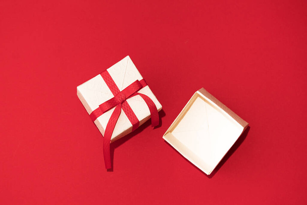 White gift box with red ribbon on red background. Concept of Valentins Day, copy space and mock up - Фото, зображення