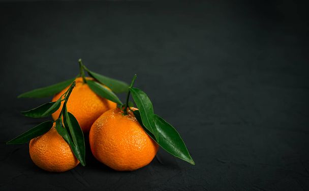 Três citrinos de tangerina frescos sobre fundo preto. Espaço para cópia. Foto de alta qualidade - Foto, Imagem
