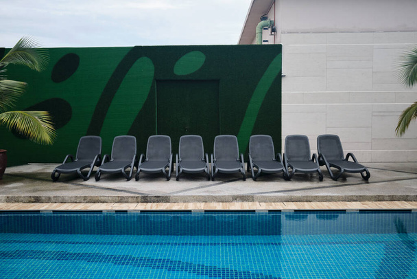 Chaise longue de couleur noire ou banc de piscine dans une rangée à la terrasse de la piscine - Photo, image