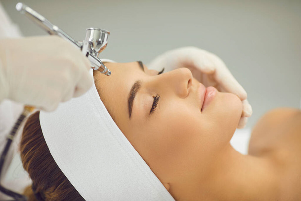 Smiling womans face getting oxygen therapy or jet peeling from cosmetologist - Foto, Imagen