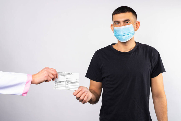 A man in medical mask receives a vaccination card from a doctor. Coronavirus concept. Safe decision. High quality photo - Foto, immagini