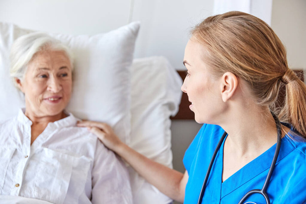 doctor or nurse visiting senior woman at hospital - Fotografie, Obrázek