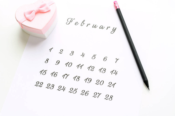 14 Φεβρουάριος ημερολόγιο με ροζ καρδιά κουτί δώρο στην κορυφή κάρτα Ημέρα του Αγίου Βαλεντίνου. - Φωτογραφία, εικόνα