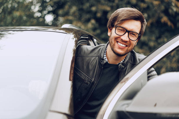 Stylish man in glasses sits in a car - Fotó, kép