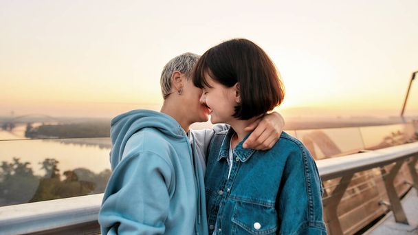 Young lesbian couple kissing outdoors, Two women enjoying romantic moments together at sunrise - Zdjęcie, obraz