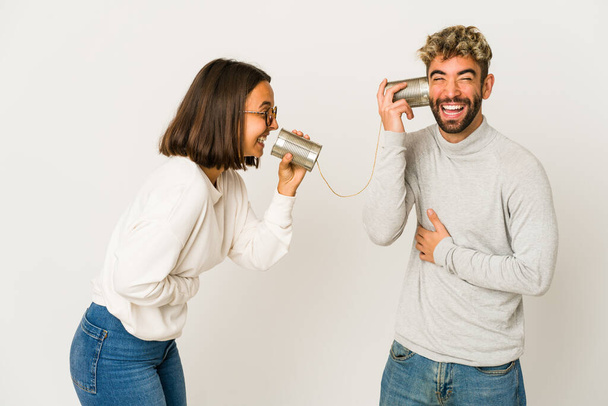 Giovani amici ispanici che parlano attraverso un sistema di lattine che ridono e si divertono. - Foto, immagini