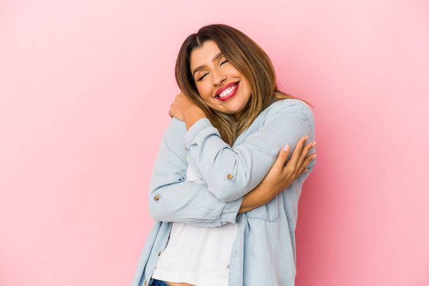 Young indian woman isolated on pink background hugs, smiling carefree and happy. - Foto, immagini