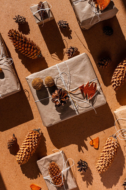 Zero waste Christmas knolling flat lay with hard shadows. Hand crafted eco gift, natural New Year jute decorations top view. Kraft paper wrapping without plastic concept. Orange zest tree,hearts,cones - Photo, Image
