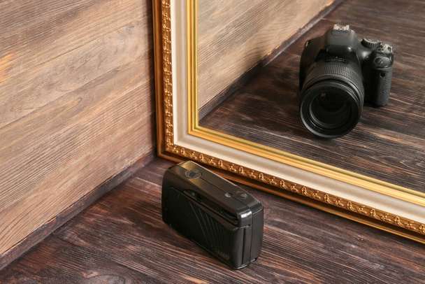 Stary aparat fotograficzny patrząc na odbicie w lustrze na drewnianym tle - Zdjęcie, obraz