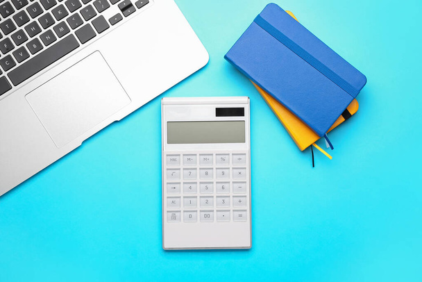 Digital calculator, notebooks and laptop on color background - 写真・画像