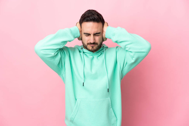 Young caucasian handsome man isolated on pink background frustrated and covering ears - Photo, image