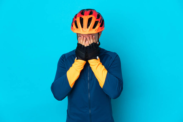 Young cyclist man isolated on blue background with tired and sick expression - Foto, imagen