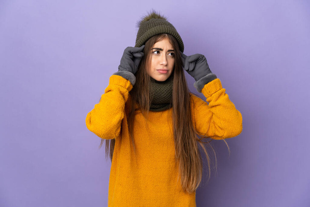 Nuori valkoihoinen tyttö talvella hattu eristetty violetti tausta ottaa epäilyksiä ja ajattelua - Valokuva, kuva