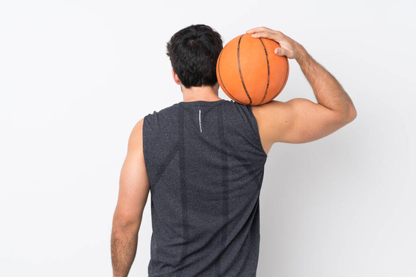 Молодой красивый мужчина с бородой на изолированном белом фоне играет в баскетбол в задней позиции - Фото, изображение