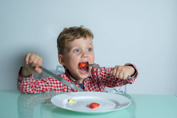 Boy eats food in the kitchen at the table. - Foto, Bild