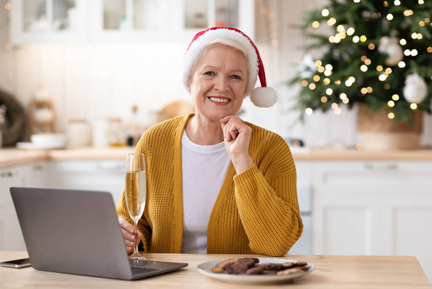 Elegante anciana con sombrero de Santa Claus usando laptop - Foto, Imagen