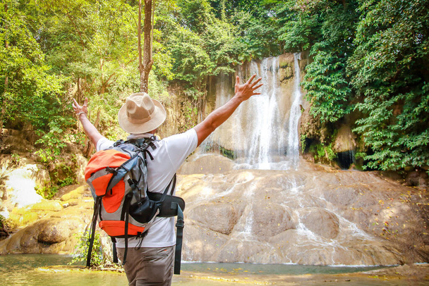 Los turistas asiáticos están caminando en el bosque para ver hermosas cascadas. Levanta ambas manos con placer. - Foto, Imagen