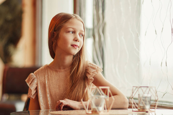 cute girl sitting at a table in a cafe - Foto, imagen