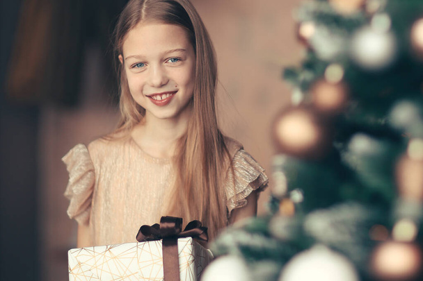 happy girl with Christmas gift standing near Christmas tree - Photo, image