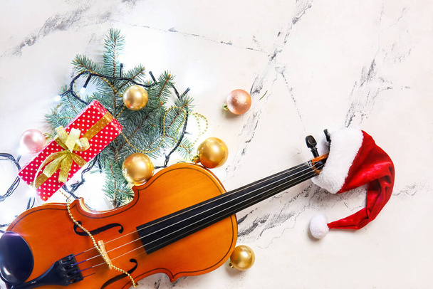 Violin with Santa Claus hat and Christmas decor on light background - Zdjęcie, obraz