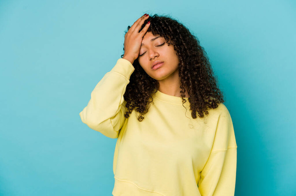 Молода афроамериканка афро-жінка ізольована втомилася і дуже сонно тримає руку на голові
. - Фото, зображення