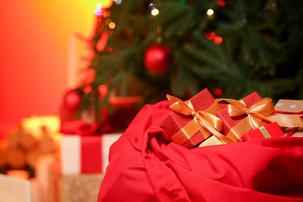 Bolso de Santa con regalos en la habitación decorada para Navidad por la noche - Foto, imagen