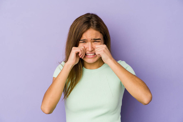 Молода худа біла дівчина підліток на фіолетовому фоні плаче і плаче безглуздо
. - Фото, зображення